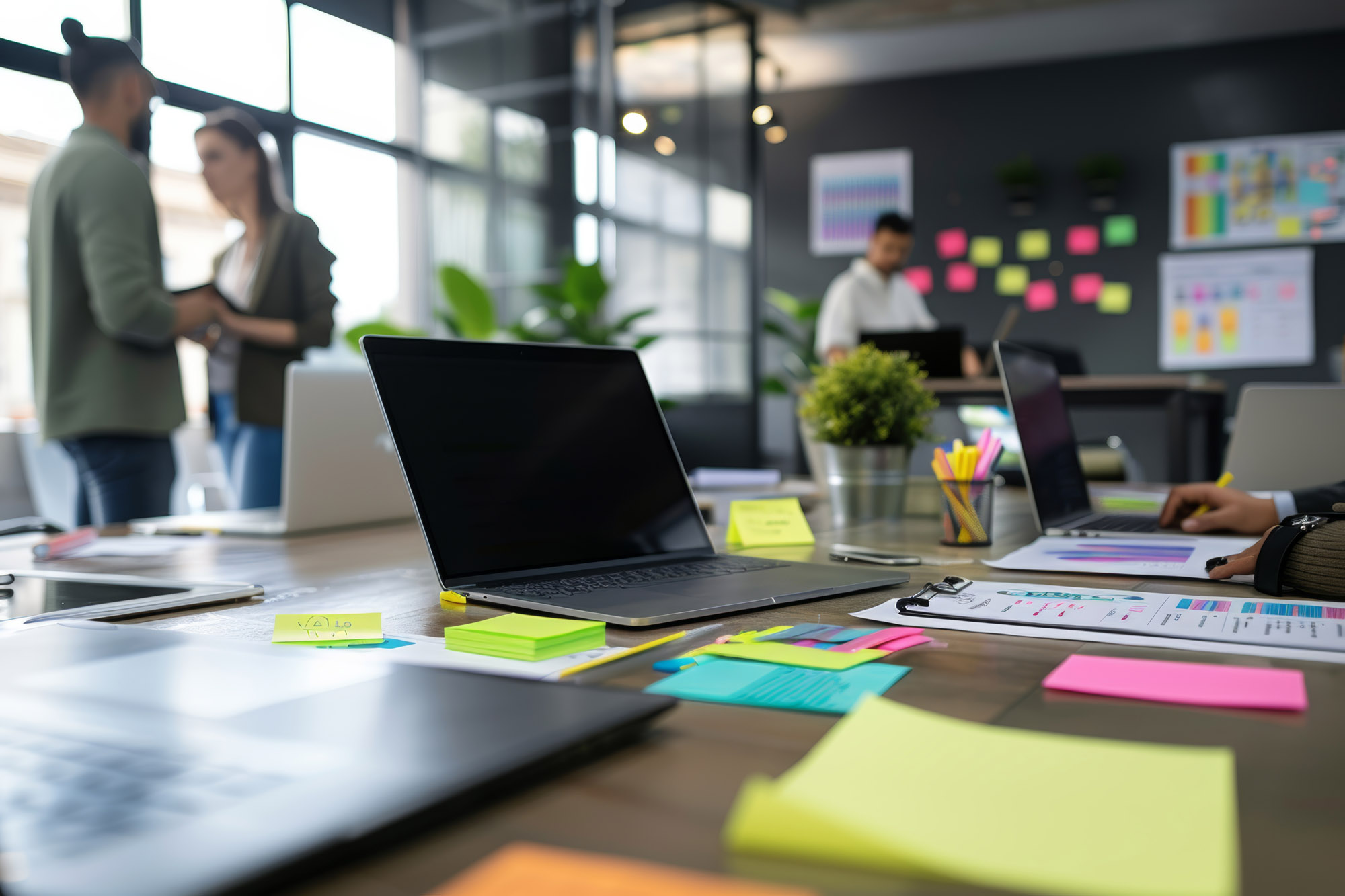 Professionals engage in a brainstorming session in a contemporary office. the workspace features laptops, tablets, vibrant sticky notes, and design sketches, a creative and productive environment with team collaboration.